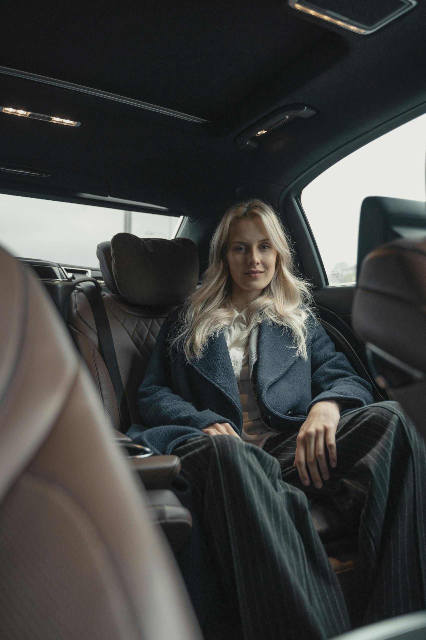 Professional woman sitting confidently in a luxury car interior, representing leadership and success.